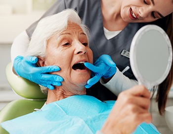 A woman’s dentist checks her dental implant.
