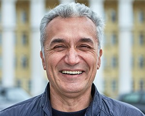 A closeup of a smiling, middle-aged man using a dental bridge