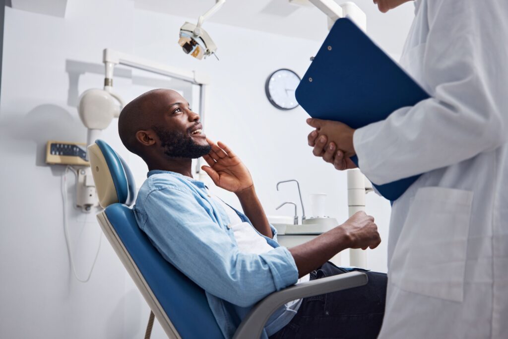 Man in blue shirt in dental chair talking to dentist